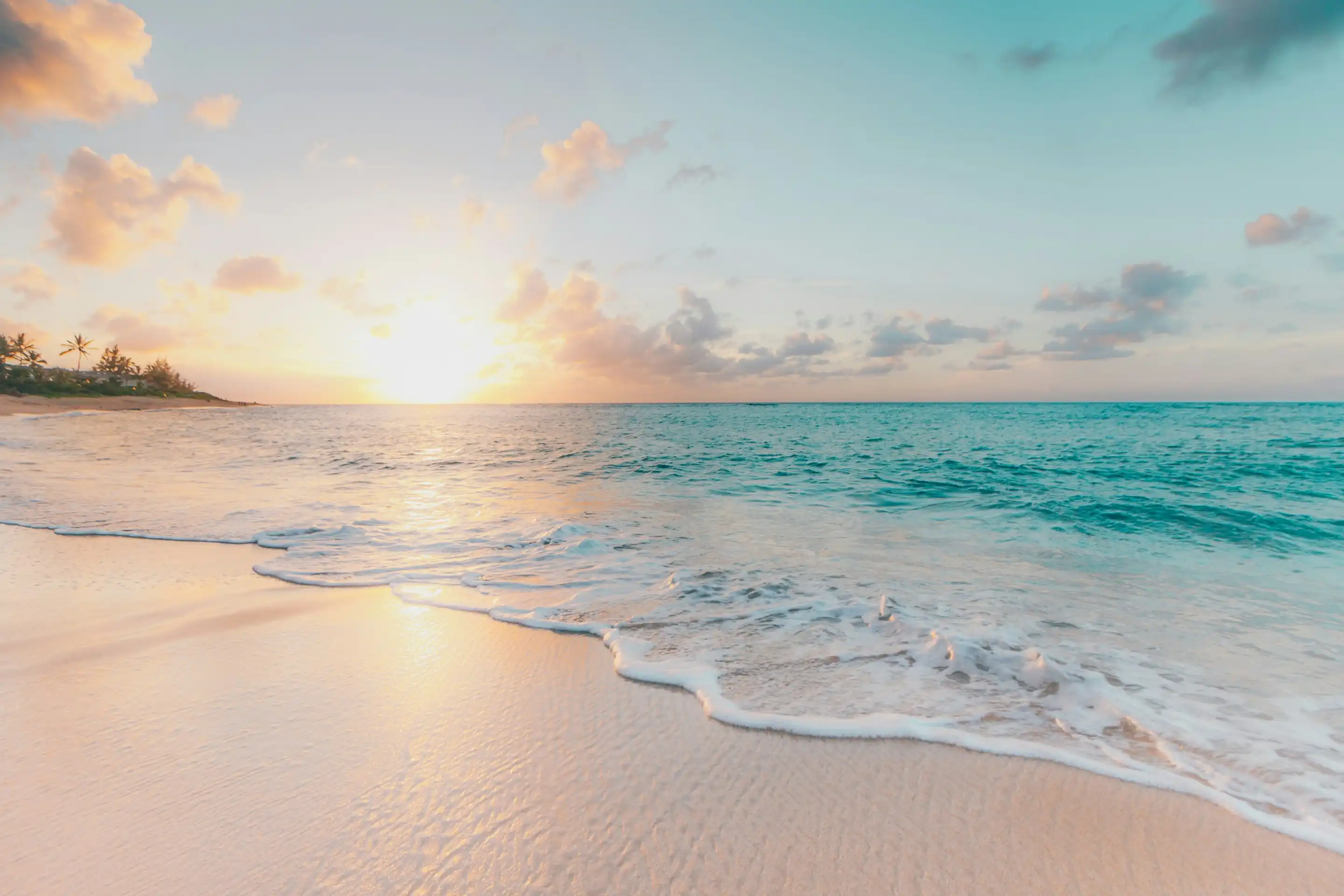 Waves on a white sand beach at sunset
